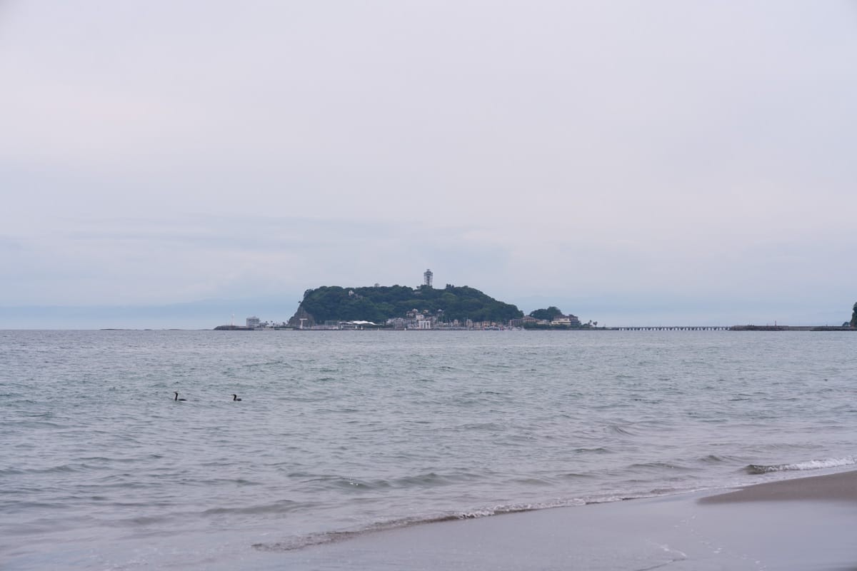 从海滩望向江之岛，阴天的海面泛着灰蓝色
